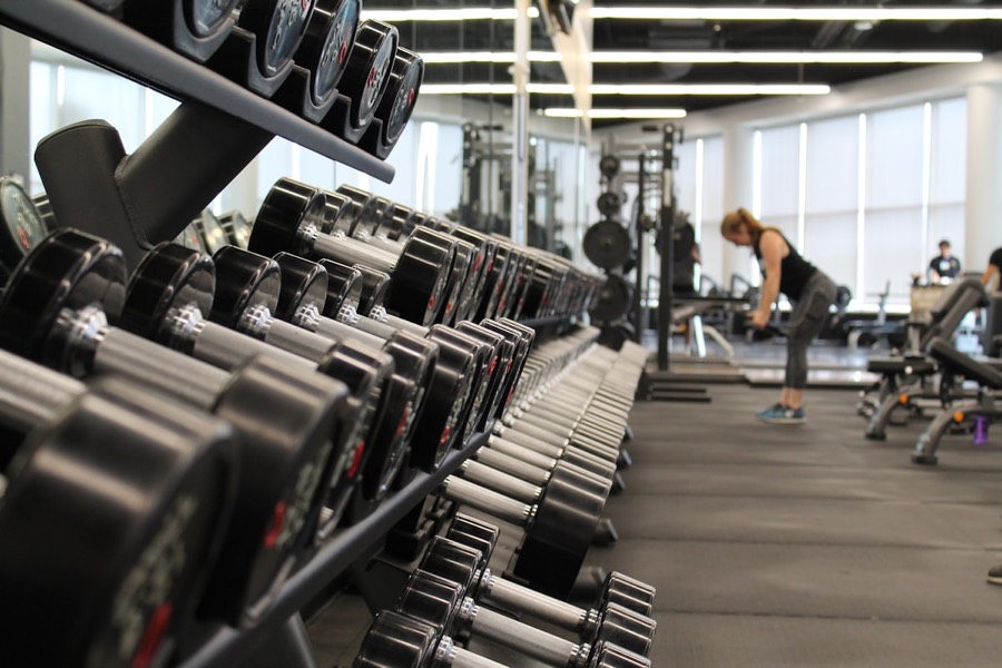 A full rack of dumbbells along a gym wall